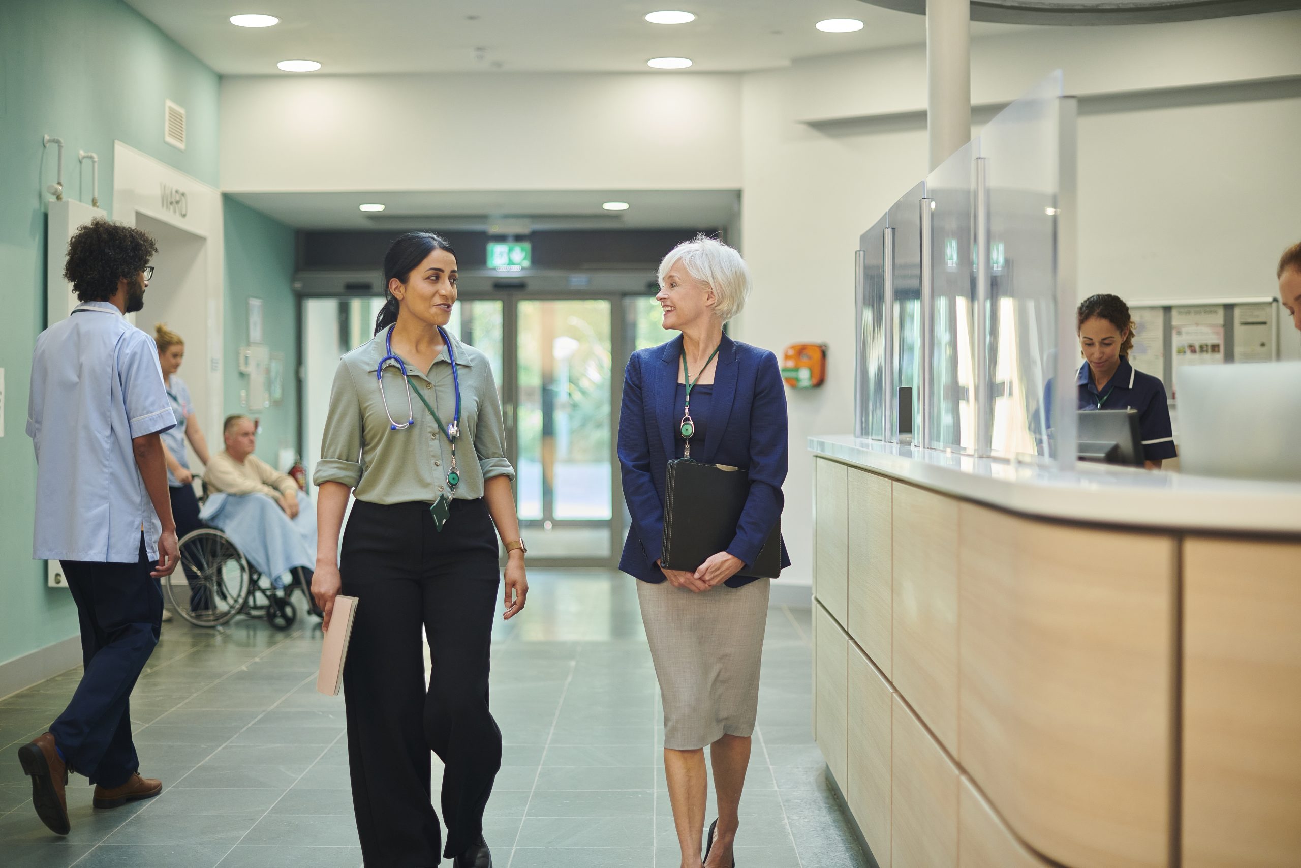 Doctors walking together in hospital past reception desk