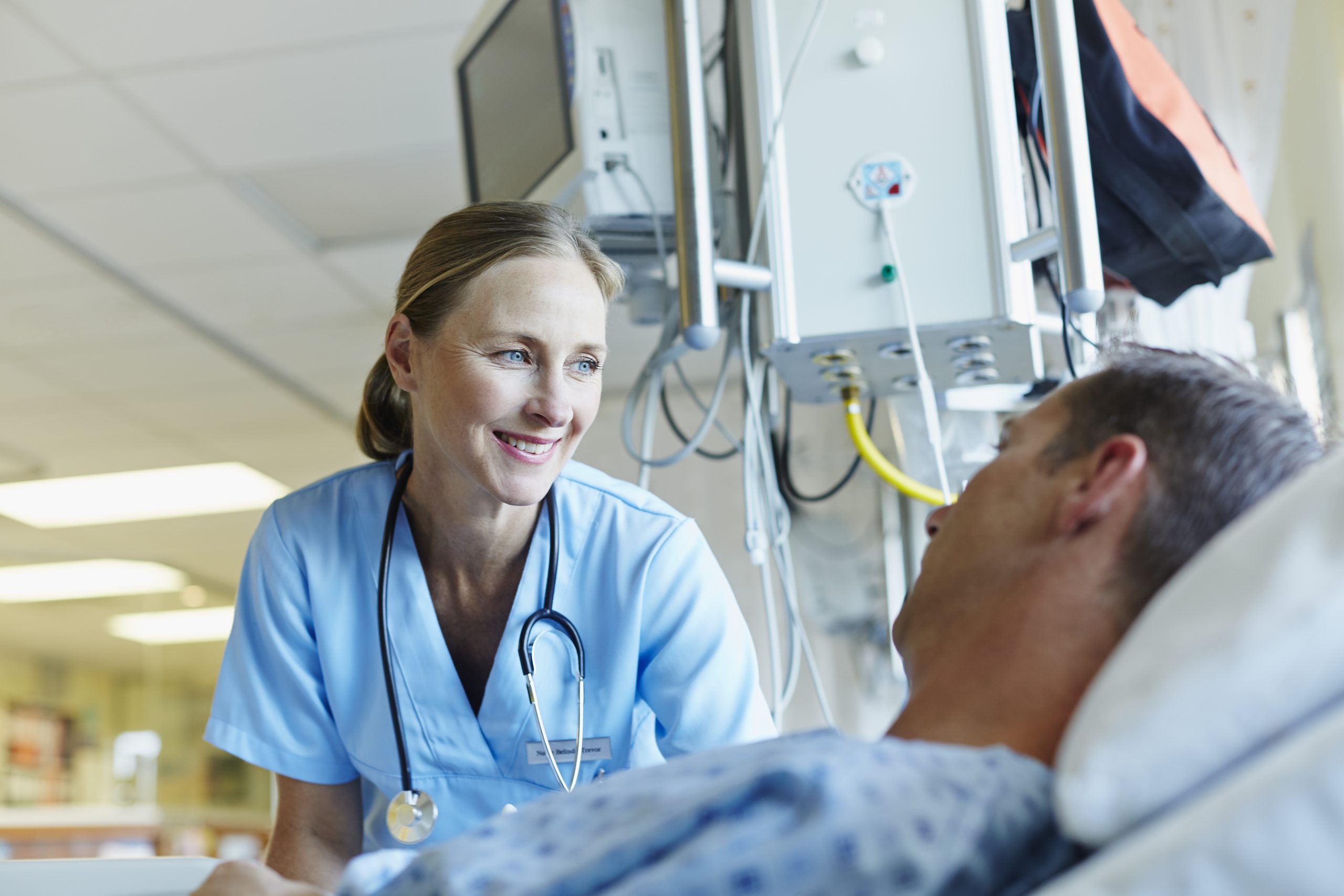 Smiling consultant doctor looking at patient in hospital ward