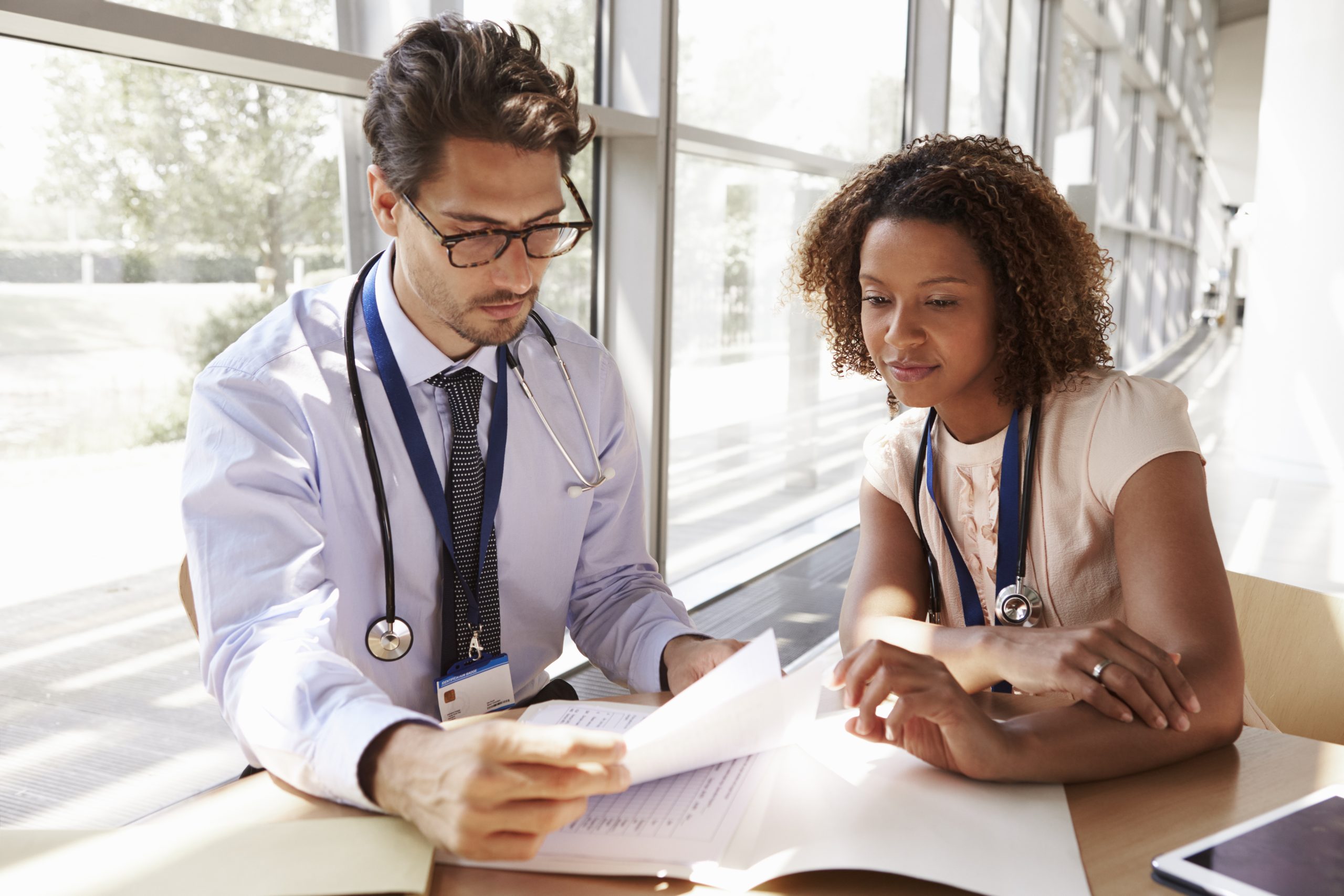 Male and female doctors reading patient medical notes